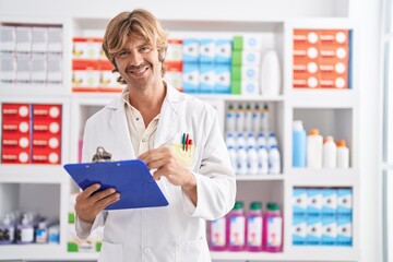 Poster - Young man pharmacist writing on clipboard at pharmacy