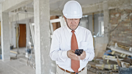 Sticker - Senior grey-haired man architect using smartphone looking around at construction site