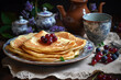 fresh pancakes with currant berries on the tea table decorated with lilac with a teapot and mug, close-up