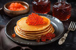 small pancakes with red caviar on a rustic wooden table, close-up