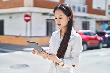 Sticker - Young chinese woman using touchpad with serious expression at street