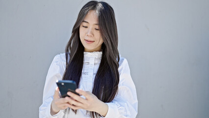 Sticker - Young chinese woman using smartphone with serious expression over isolated white background