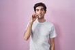 © Krakenimages.com - Young hispanic man standing over pink background mouth and lips shut as zip with fingers. secret and silent, taboo talking