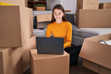 Poster - Young caucasian woman using laptop sitting on floor at new home