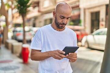 Sticker - Young bald man using touchpad with serious expression at street