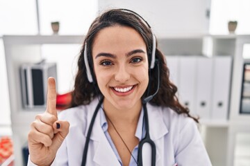 Sticker - Young doctor woman working on online appointment smiling with an idea or question pointing finger with happy face, number one