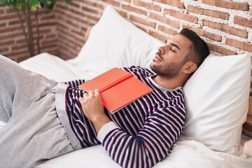 Sticker - Young hispanic man holding book lying on bed sleeping at bedroom