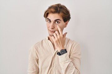 Wall Mural - Young man standing over isolated background pointing to the eye watching you gesture, suspicious expression