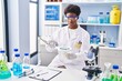 © Krakenimages.com - African american woman wearing scientist uniform using magnifying glass at laboratory