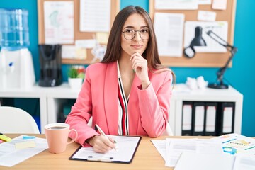 Sticker - Young hispanic woman working at the office wearing glasses looking confident at the camera smiling with crossed arms and hand raised on chin. thinking positive.