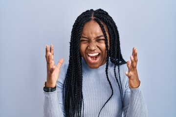 Poster - African american woman standing over blue background celebrating mad and crazy for success with arms raised and closed eyes screaming excited. winner concept