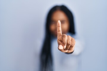 Sticker - African american woman standing over blue background pointing with finger up and angry expression, showing no gesture