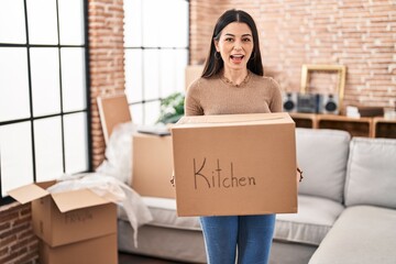 Sticker - Young woman moving to a new home holding box celebrating crazy and amazed for success with open eyes screaming excited.