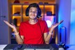 © Krakenimages.com - Young hispanic man playing video games clueless and confused expression with arms and hands raised. doubt concept.