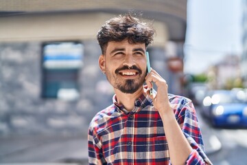 Young hispanic man smiling confident talking on the smartphone at street