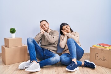 Poster - Young couple moving to a new home sleeping tired dreaming and posing with hands together while smiling with closed eyes.