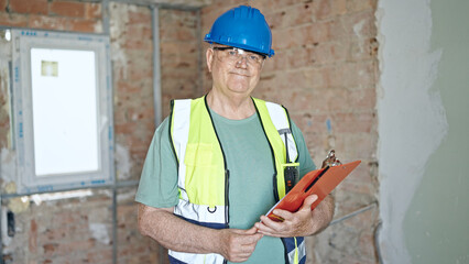 Poster - Middle age grey-haired man builder smiling confident reading document on clipboard at construction site