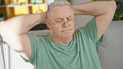 Poster - Middle age grey-haired man relaxed with hands on head sitting on sofa at home