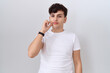 © Krakenimages.com - Young non binary man wearing casual white t shirt mouth and lips shut as zip with fingers. secret and silent, taboo talking