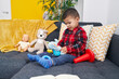 © Krakenimages.com - Adorable hispanic boy sitting on sofa playing with elephant toy at home
