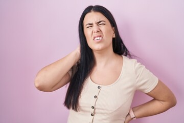 Canvas Print - Young hispanic woman standing over pink background suffering of neck ache injury, touching neck with hand, muscular pain