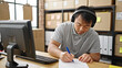 © Krakenimages.com - ecommerce business worker using computer and headphones writing on document at office