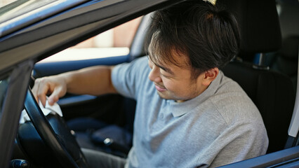  sitting on car cleaning steering wheel at street