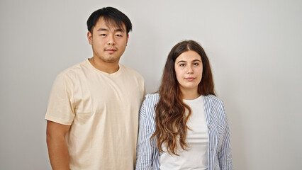 Man and woman couple standing together with serious expression over isolated white background