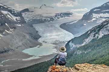 Canvas Print - Woman on cliff over glacier lake in Canadian Rockies. Banff Natioanal park. Columbia Icefield. Athabaska glacier. Alberta. Canada