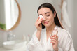 © New Africa - Beautiful woman removing makeup with cotton pad indoors