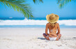 Relax, back view of a woman on the beach and sitting on the sand, Summer vacation or holiday break, freedom or adventure and female person relaxing at the sea with blue sky for peace in nature
