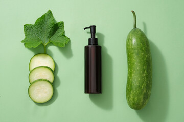 Wall Mural - Minimal flat lay scene for advertising - an amber pump bottle with fresh winter melon, slices and leaf decorated on a light green background. Advertising scene for cosmetic skin care and body care