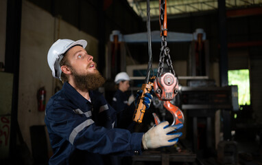 Two technicians inspecting and testing the operation of lifting cranes in heavy industrial plants.