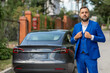 © Михаил Решетников - Caucasian bearded man in a blue suit stands near a black car in the countryside in summer.