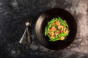 Healthy food stir fried shrimp asparagus teriyaki in plate on black slate table.