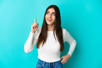 Wall Mural - Young caucasian woman isolated on blue background pointing up and surprised