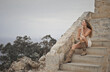 © olly - woman sitting on the steps of an old house looks at the view