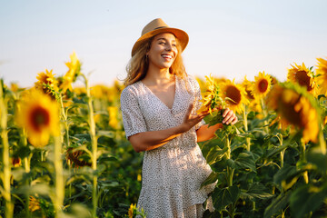 beautiful woman posing in a field of sunflowers in a dress and hat. fashion, lifestyle, travel and v