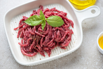 Wall Mural - Beige serving tray with raw fresh ground beef meat, horizontal shot on a beige stone background, middle closeup