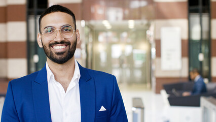 portrait of attractive professional indian male looking to camera and smiling, with space for text