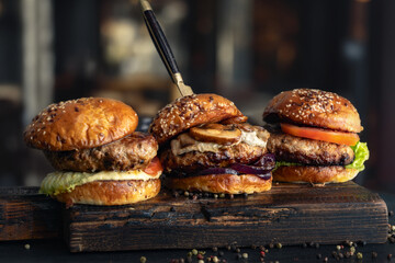 Poster - Close-up three different brutal burgers on wooden board in a burger joint