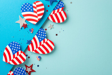 Wall Mural - Veterans Day USA imaginative celebrations. Top view of patriotic adornments: hearts decorated with American flag pattern, glittering stars, confetti on bicolor blue surface with space for text or ad