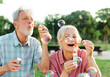 © Lumos sp - woman man senior couple  together elderly active happy retirement bubble soap blowing fun blow vitality bonding park outdoor leisure park fun