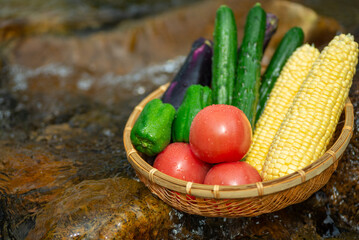 清流とザルに入れた夏野菜