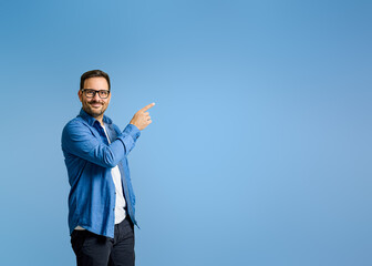 Portrait of confident salesman pointing at product with copy space while standing on blue background
