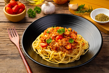 Wall Mural - Spaghetti with canned tuna fish in tomato sauce, pasta with a meat based bolognese tomatoes,served in black plate