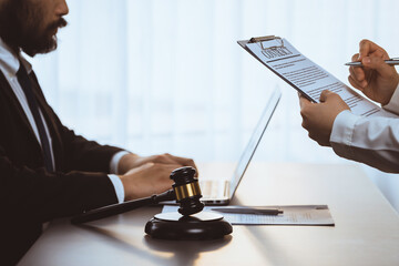 Wall Mural - Focus gavel hammer for righteous and equality judgment with blur background of lawyer colleagues or legal team working with laptop, drafting legal documents for litigation at law firm. Equilibrium