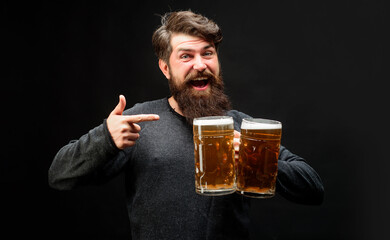 Wall Mural - Celebration oktoberfest festival. Smiling man pointing with finger to mugs of beer. Bearded man with lager beer mugs at bar or pub. Stylish guy with craft beer. Bearded male tasting fresh brewed beer.