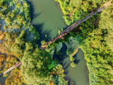 Fototapeta Dmuchawce - Aerial view of rural wooden bridge over small forest river.