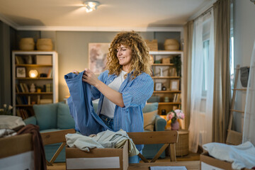 Wall Mural - One young adult woman prepare wardrobe clothes for charity donation